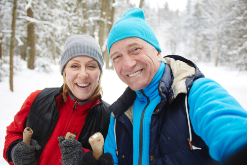 Older couple smiling while hiking in snow