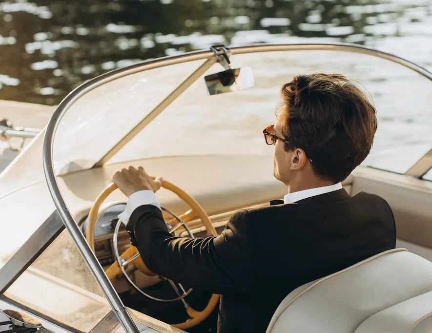 Young man in black suit driving boat