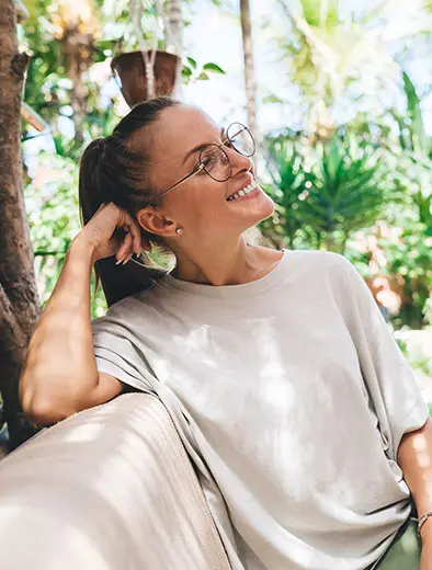 Cheerful woman in classic eyewear glasses resting at terrace in courtyard