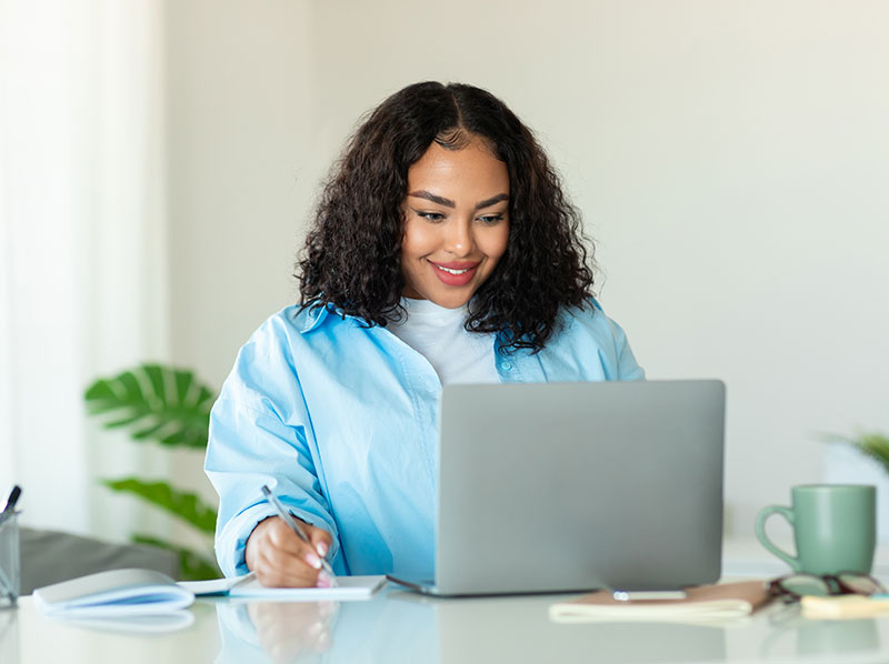 Black woman looking at laptop smiling