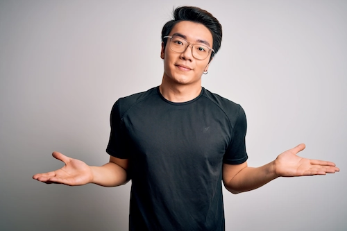 Millennial man with glasses shrugging his shoulders