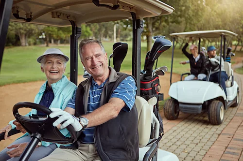 Older couple riding happily in a golf cart