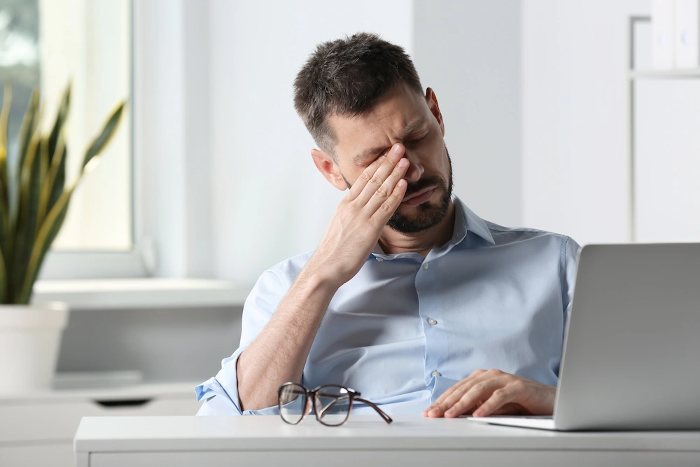 young business man rubbing dry eyes